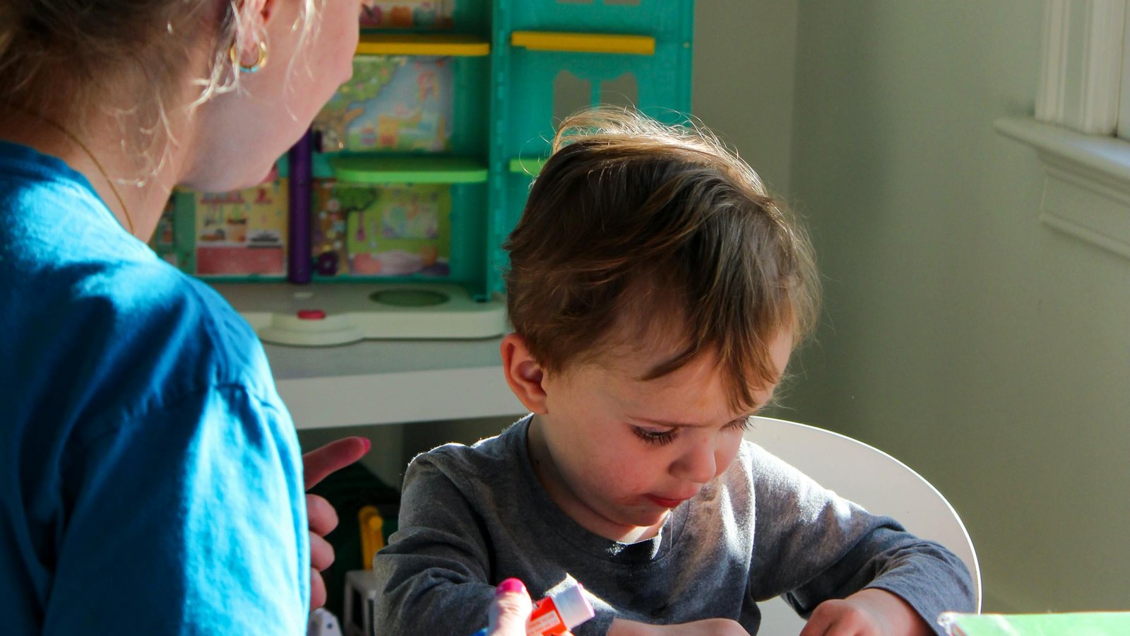 Maman qui accompagne son jeune enfant sur une activité de bricolage à la maison
